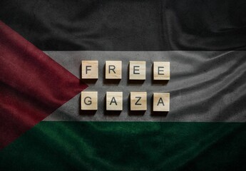 Free Gaza text written with wooden tiles on textured flag of Palestine