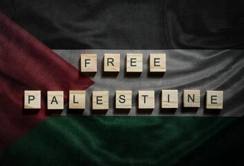Free Palestine text written with wooden tiles on textured flag of Palestine