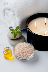 Spa treatments, massage, relaxation and beauty concept. Spa set. Towel, candles, aroma oil, sea salt, massage stone on a marble background