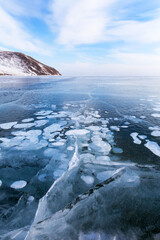 Beautiful winter landscape of frozen Baikal Lake in cold February day. Natural seasonal background with blue ice surface with white bubbles and cracks.  Winter ice travel and outdoor recreation