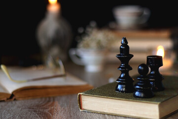 Vintage books, reading glasses, gold pen, hand model, gold jewelry, scented candles, flowers, chess pieces and cup of tea or coffee on the table. Dark academia concept. Selective focus. - obrazy, fototapety, plakaty