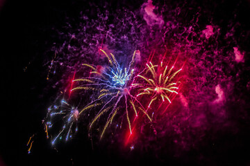 red and purple fireworks burst into various shapes in the sky	
