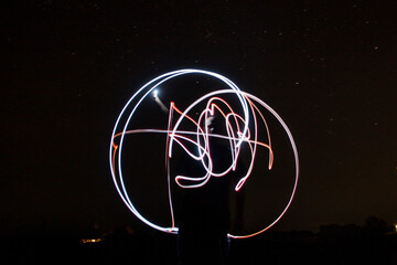 The name Vova is drawn in the air with light against the background of the starry sky