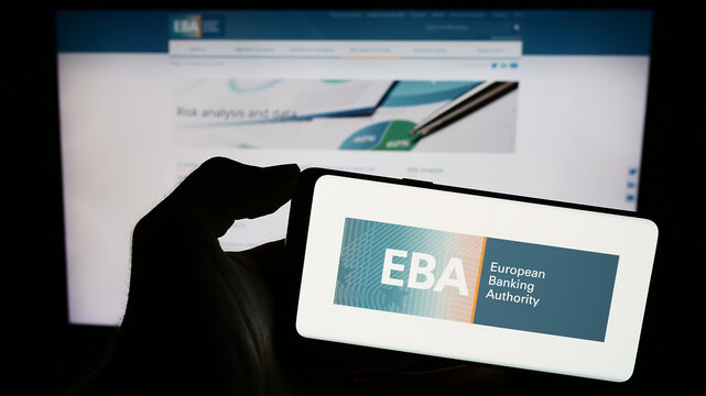 Stuttgart, Germany - 10-20-2023: Person holding mobile phone with logo of EU institution European Banking Authority (EBA) in front of web page. Focus on phone display.