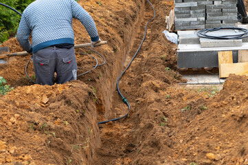a worker digging a trench for electric cable, outdoor shot, no people