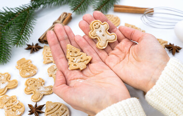 Womens hands hold Christmas cookies in the shape of a gingerbread man and Christmas tree. Winter holidays concept. Close-up.