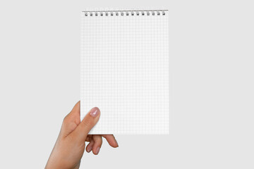 Female Hand Holding Notepad with Blank Page Isolated On Gray Neutral Studio Background. Close Up. Chroma Key Screen. Woman's Hand with Empty Card Paper MockUp. Advertisement gesture. Notebook Mock Up.