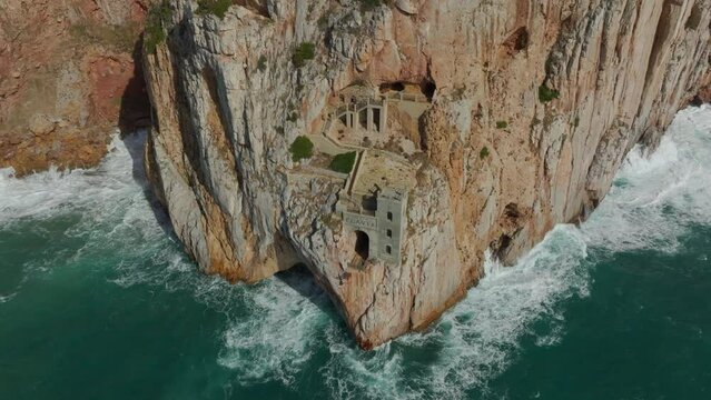 Orbital aerial view of the historic mining port of Porto Flavia in the south of Sardinia and where the sea hits the cliff.