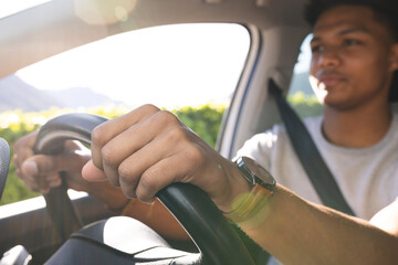 Happy african american man with hands on steering wheel driving car on sunny day