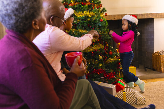 Happy african american grandparents and grandchildren and decorating christmas tree, copy space