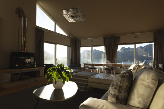 Interior of sunny open plan lounge and dining areas with mountain views, copy space