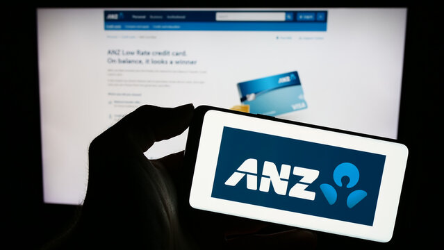 Stuttgart, Germany - 10-28-2023: Person holding smartphone with logo of Australia and New Zealand Banking Group Limited (ANZ) in front of website. Focus on phone display.