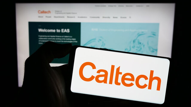 Stuttgart, Germany - 10-28-2023: Person holding mobile phone with logo of university California Institute of Technology (Caltech) in front of web page. Focus on phone display.