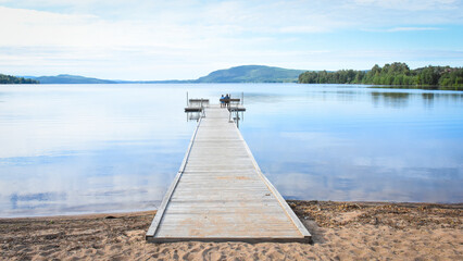 Mother and daughter sitting on a wooden pier in summer in Sweden