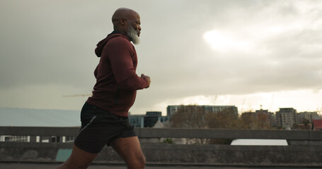 Man, city or senior runner with cardio workout in training, road fitness for health lifestyle. African athlete, retirement or wellness for strong body in leisure, cape town or exercise on urban road - obrazy, fototapety, plakaty