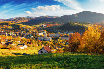 rural landscape of carpathian mountains in evening light. beautiful countryside scenery in autumn season with fields on the hills and village in the valley