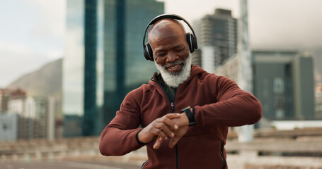 Man, headphones and smart watch in city for fitness, exercise results and workout performance. Happy senior african runner check timer, clock and healthy training progress with music in urban street