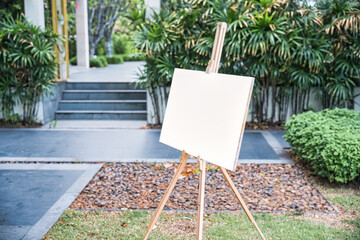 White board canvas on wooden easel in the garden, Welcome sign about wedding event - obrazy, fototapety, plakaty