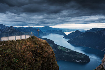 Fronalpstock with cross on summit and moody sky overlooking Lake Lucerne at Schwyz, Switzerland