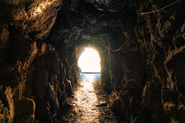 Natural cave mining underground tunnel rock and golden light at the destination