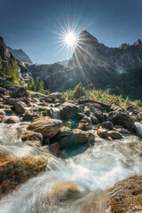 Swiss Alps of Wetterhorn peak with sunburst shine and waterfall flowing in sunny day at...