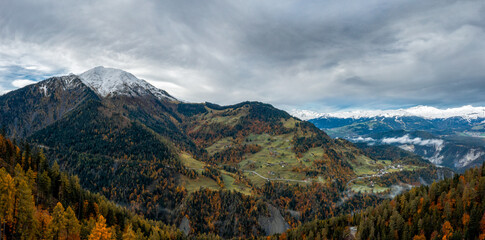 mountain landscape in the Swiss Alps with snow-capped peaks and autum color forest