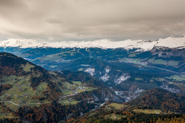 mountain landscape in the Swiss Alps with snow-capped peaks and autum color forest
