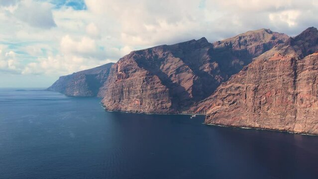 Aerial of hight mountain cliffs Los Gigantes and tourist resort on Tenerife island. Volcanic rocks, ocean, hotels in village and yacht harbor. Landmark of Canary island.