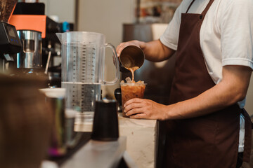 Barista pouring brew coffee making menu ice coffees at coffee shop. SME business coffee shop...
