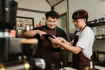 Barista training job at coffee shop. Two Asian man colleague barista at coffee shop. SME business...