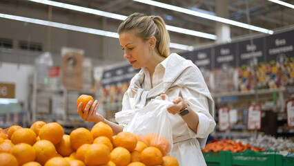 Woman buy healthy food fruit market. Customer take ripe orange eco store. 30s lady keep raw diet....
