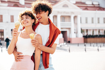 Smiling beautiful woman and her handsome boyfriend. Woman in casual summer clothes. Happy cheerful family. Couple posing on the street background at sunny day. Eating tasty ice cream in waffles cone