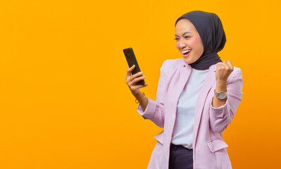 Cheerful asian woman showing smartphone blank screen and celebra