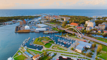 A breathtaking aerial drone photo of Kołobrzeg's marina in Poland captures a picturesque scene. The view showcases a multitude of yachts, sailboats, fishing boats and ships. - obrazy, fototapety, plakaty