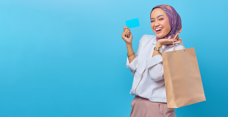 Portrait of a cheerful woman holding shopping bags and credit ca