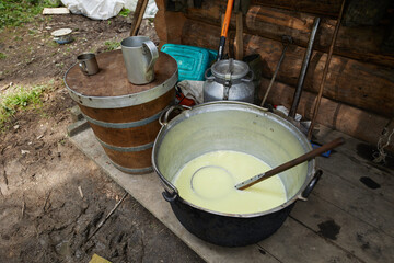 Fototapeta premium A mountain shepherd cooks cheese in a cauldron over a fire. Traditional cheese making in the mountains.