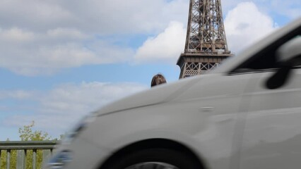 Young white girl walking by Eiffel Tower and touching hair as car passes, Paris 