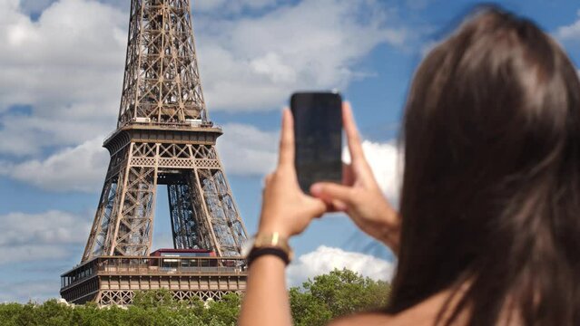 Brunette woman taking picture with cell phone of Eiffel Tower, Paris, France
