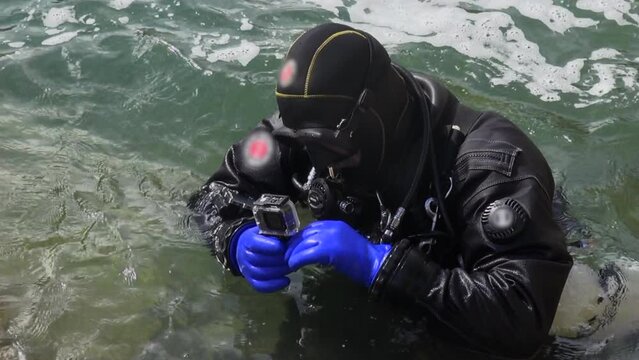 Technical diver in gear inspects underwater camera at chaotic river