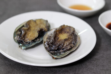 Abalone on white plate. Close-up images of seafood dishes.

