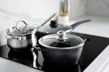 The saucepans stand on an electric induction stove. Modern modernized kitchen in the style of minimalism. Kitchen interior