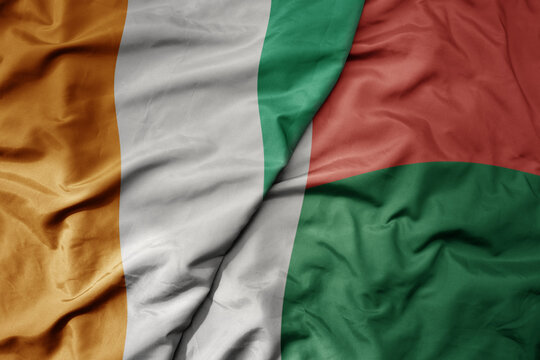 big waving national colorful flag of cote divoire and national flag of madagascar .