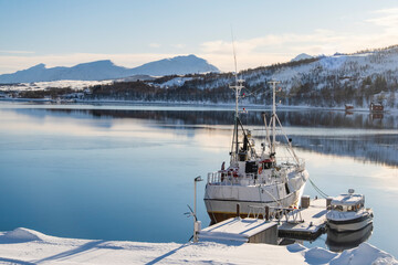 Fishing boat in harbor of Norther Norway. Red rorbu, fishing trawler and cold sea water in sunny summer day