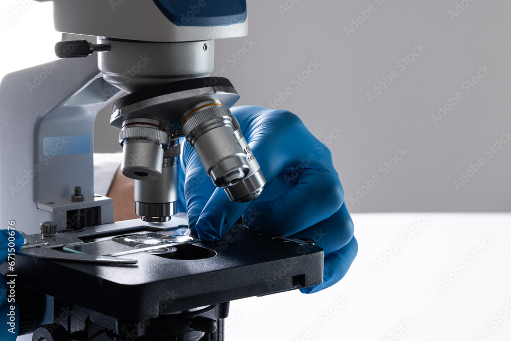 Poster close up of hand in glove using laboratory microscope and copy space on white background