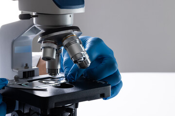 Close up of hand in glove using laboratory microscope and copy space on white background