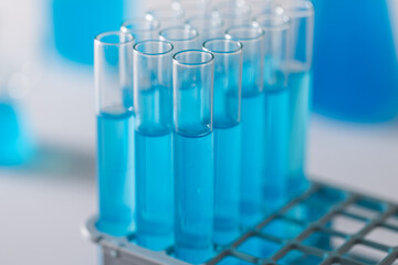 Close up of laboratory test tubes with blue liquid and copy space on white background