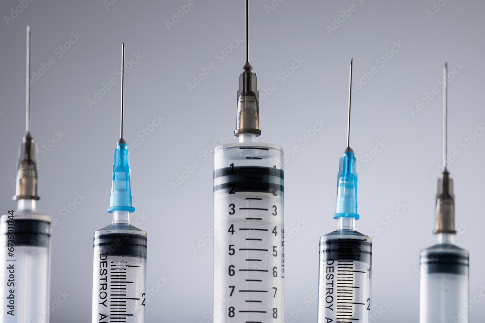 Poster close up of laboratory syringes with needles and copy space on grey background
