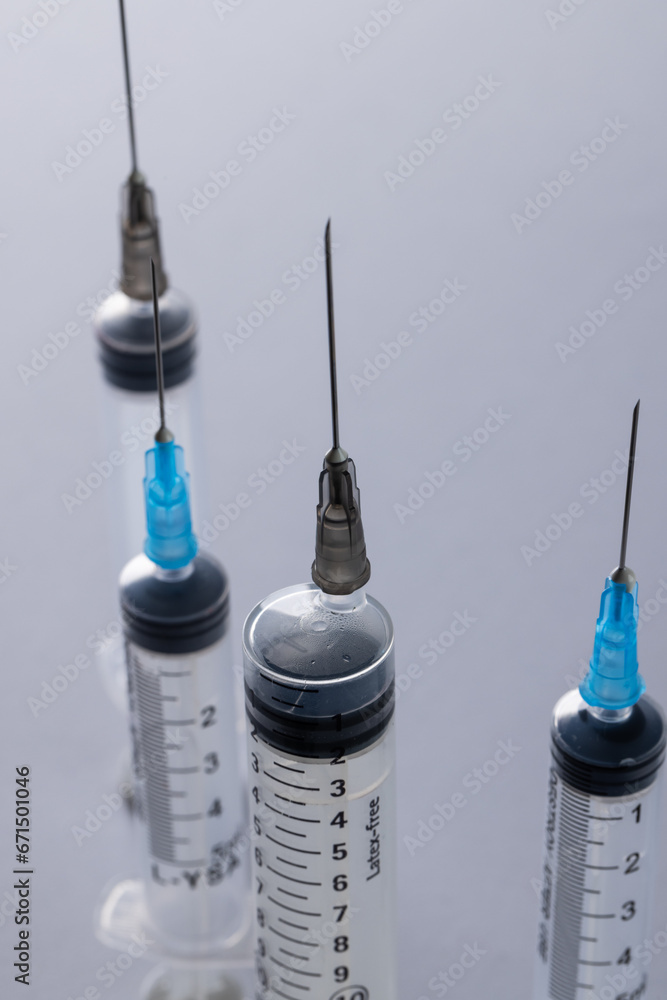 Poster vertical image of laboratory syringes with needles and copy space on grey background