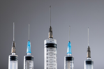 Close up of laboratory syringes with needles and copy space on grey background