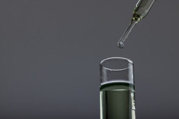 Vertical image of close up of laboratory test tube and pipette with copy space on grey background